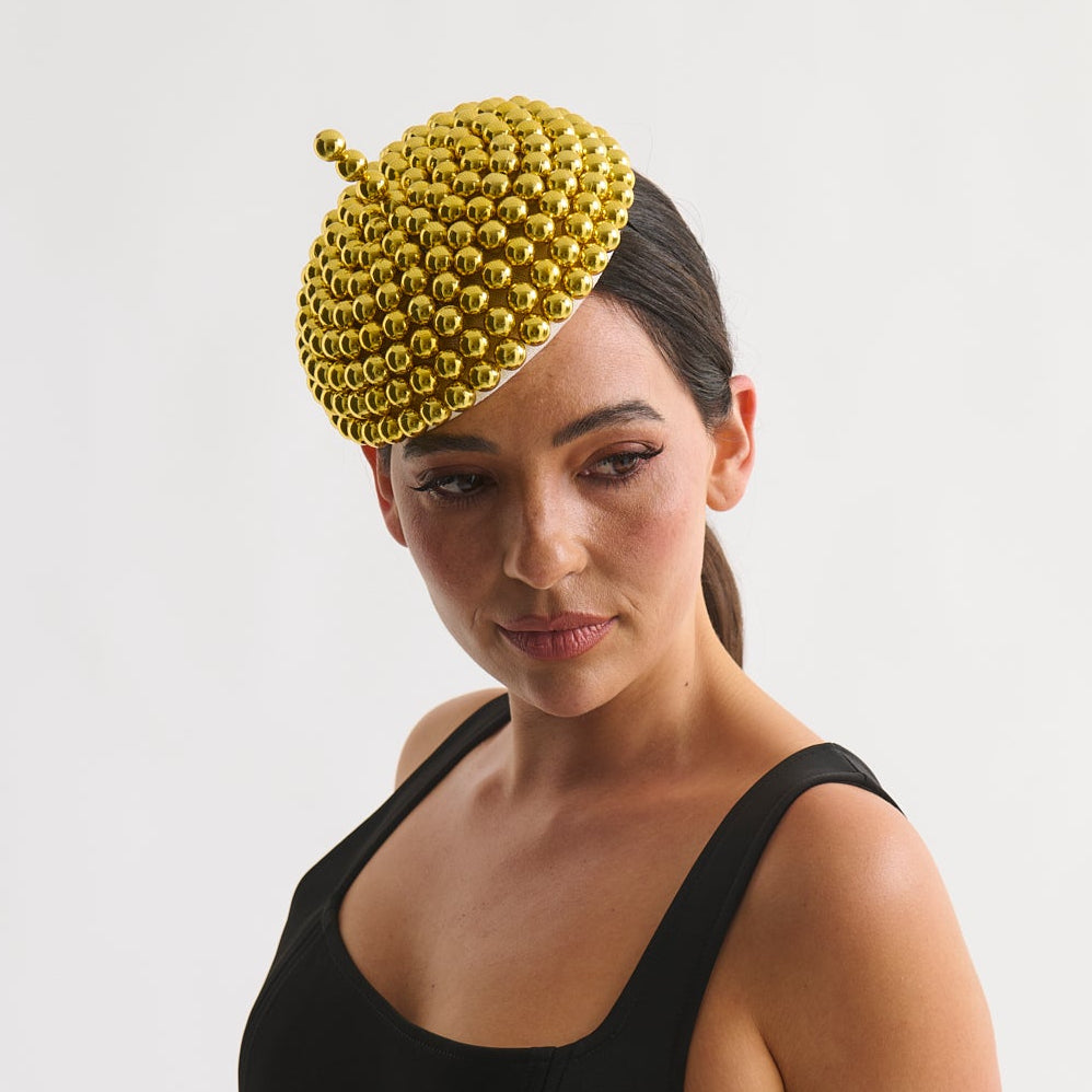 Woman wearing a black dress and yellow headpiece against a white background