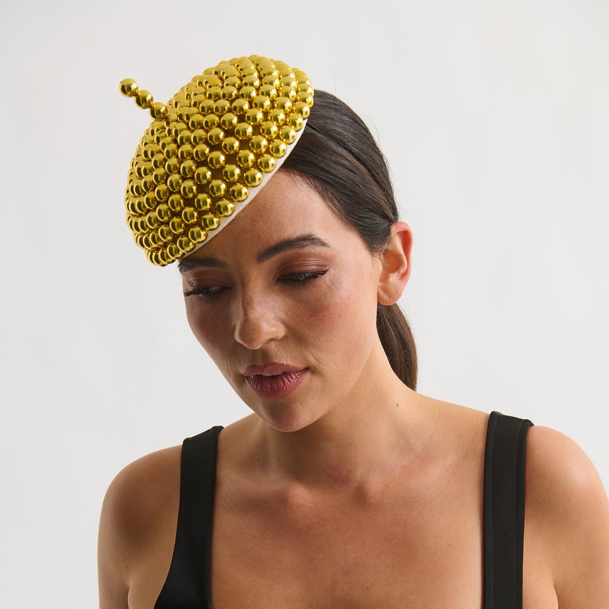 Woman wearing a black dress and a gold beaded headpiece against a white background