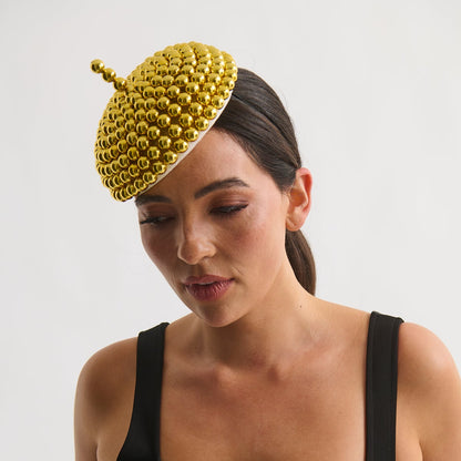 Woman wearing a black dress and a gold beaded headpiece against a white background
