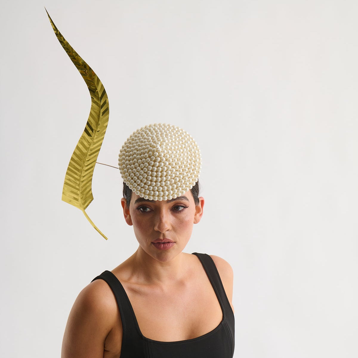 Woman wearing a decorative headpiece with a leaf on a plain background