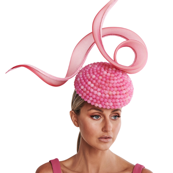 Woman wearing a pink beaded headpiece with a decorative ribbon on a white background