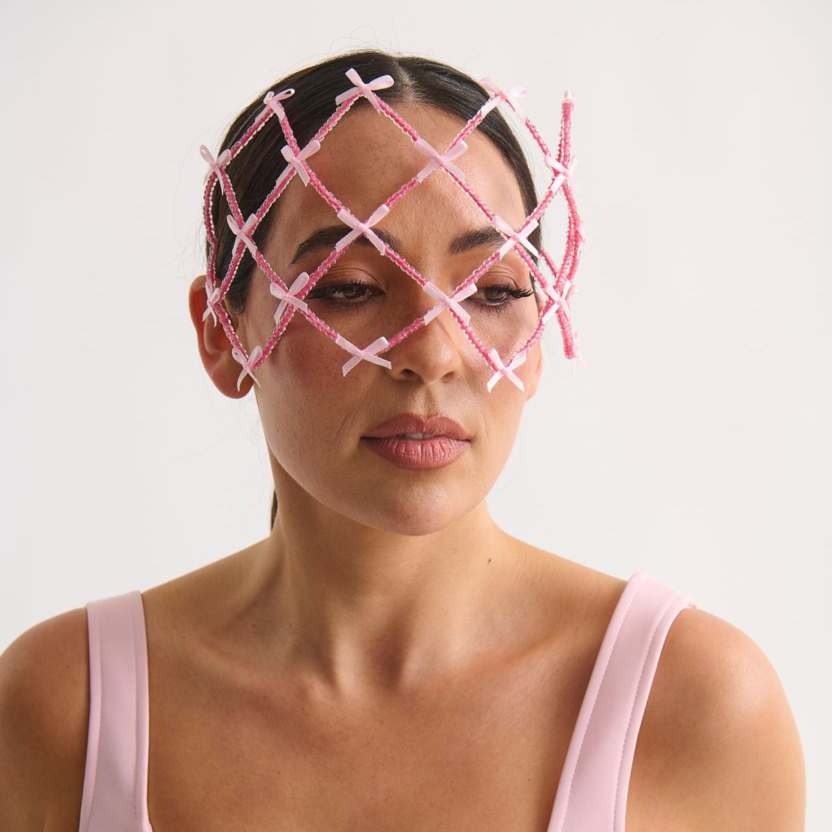 Woman wearing a pink face mask with a lattice design on a white background