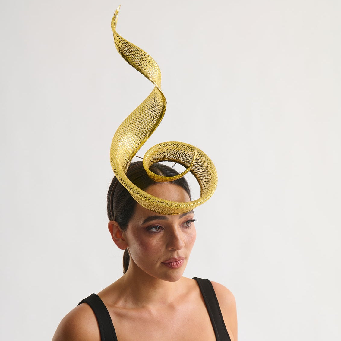 Woman wearing a black dress with a gold woven crinoline headpiece against a white background