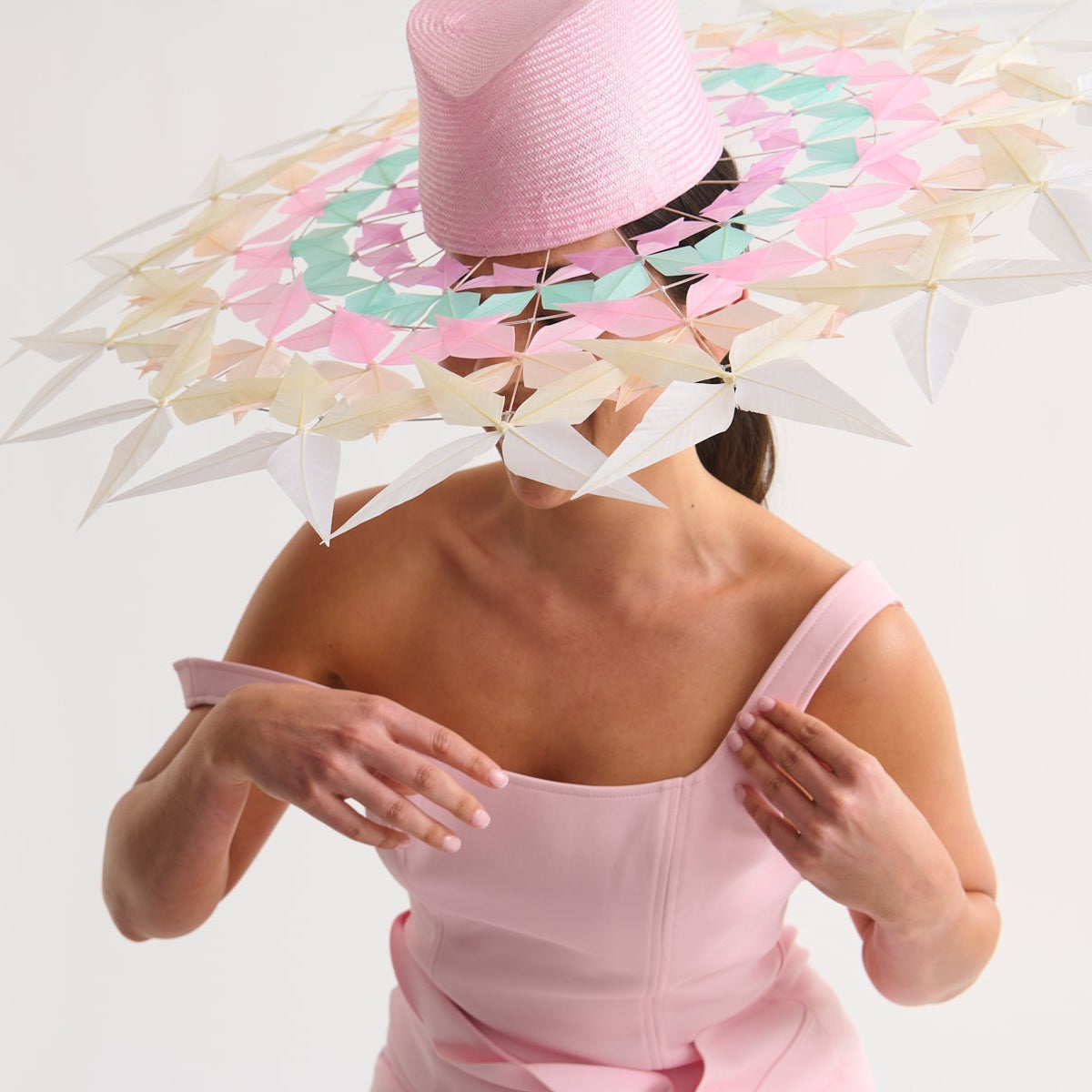 Woman wearing a colorful straw hat and pink dress on a white background